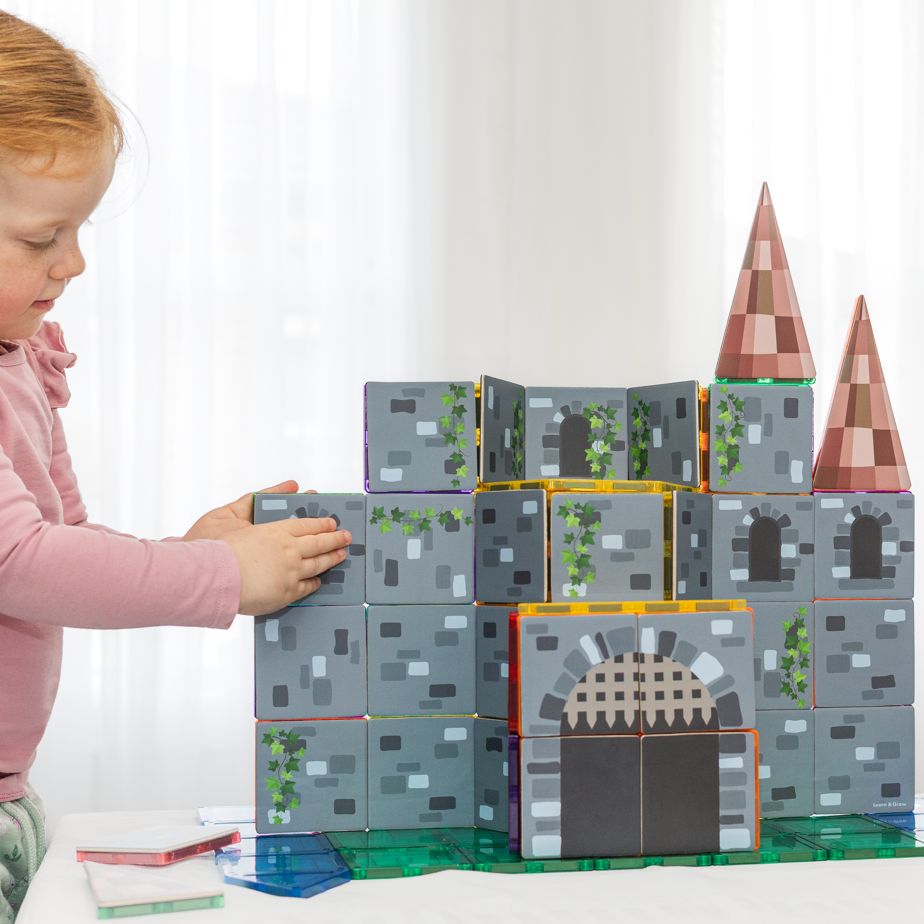 Child playing with a magnetic tile castle built from the Castle Pack