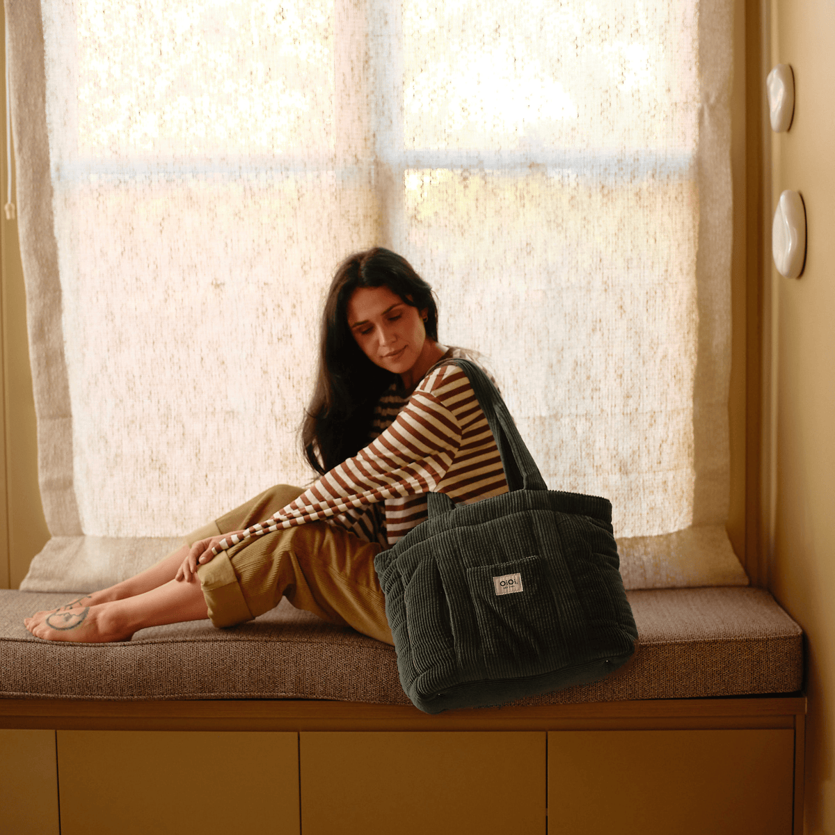 Parent carrying the OiOi Everyday Tote nappy bag in moss green corduroy