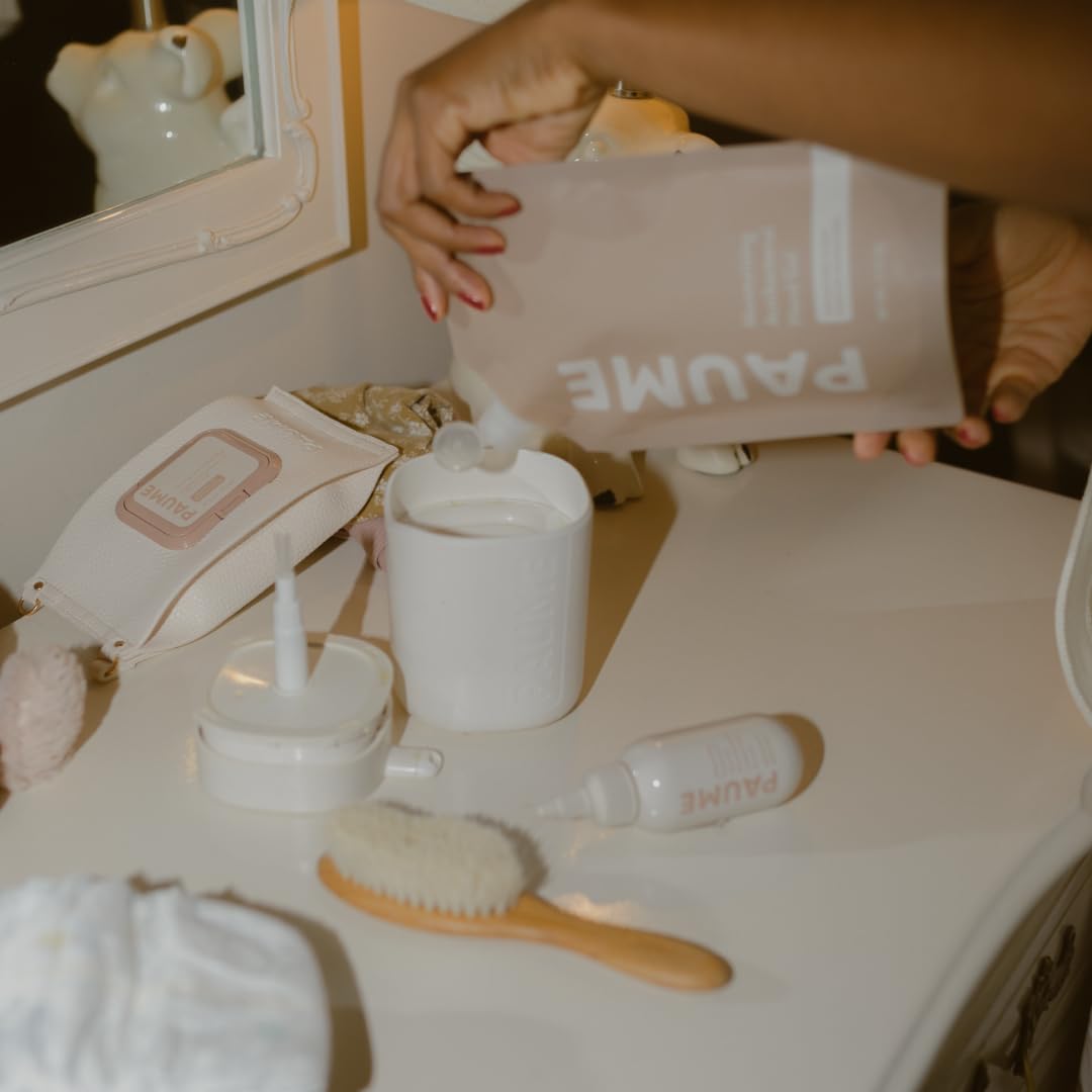Person pouring a product from a PAUME container into a white container on a vanity with various skincare items.