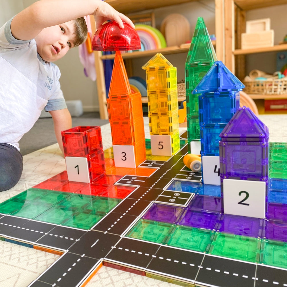 Child playing with dome tiles and Road Pack toppers in a playroom