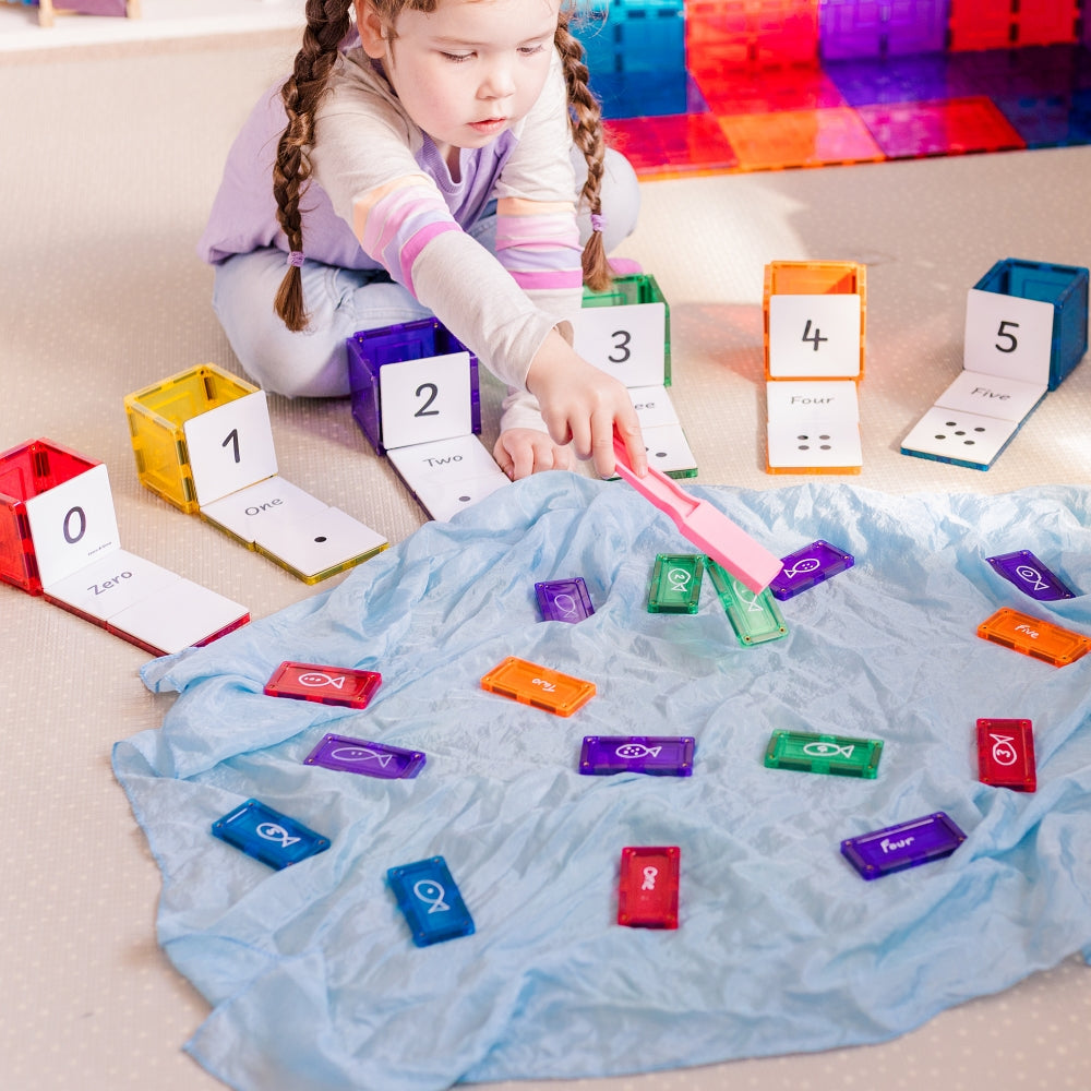 Child using a magnetic wand with Numbers Pack toppers on a blue play silk