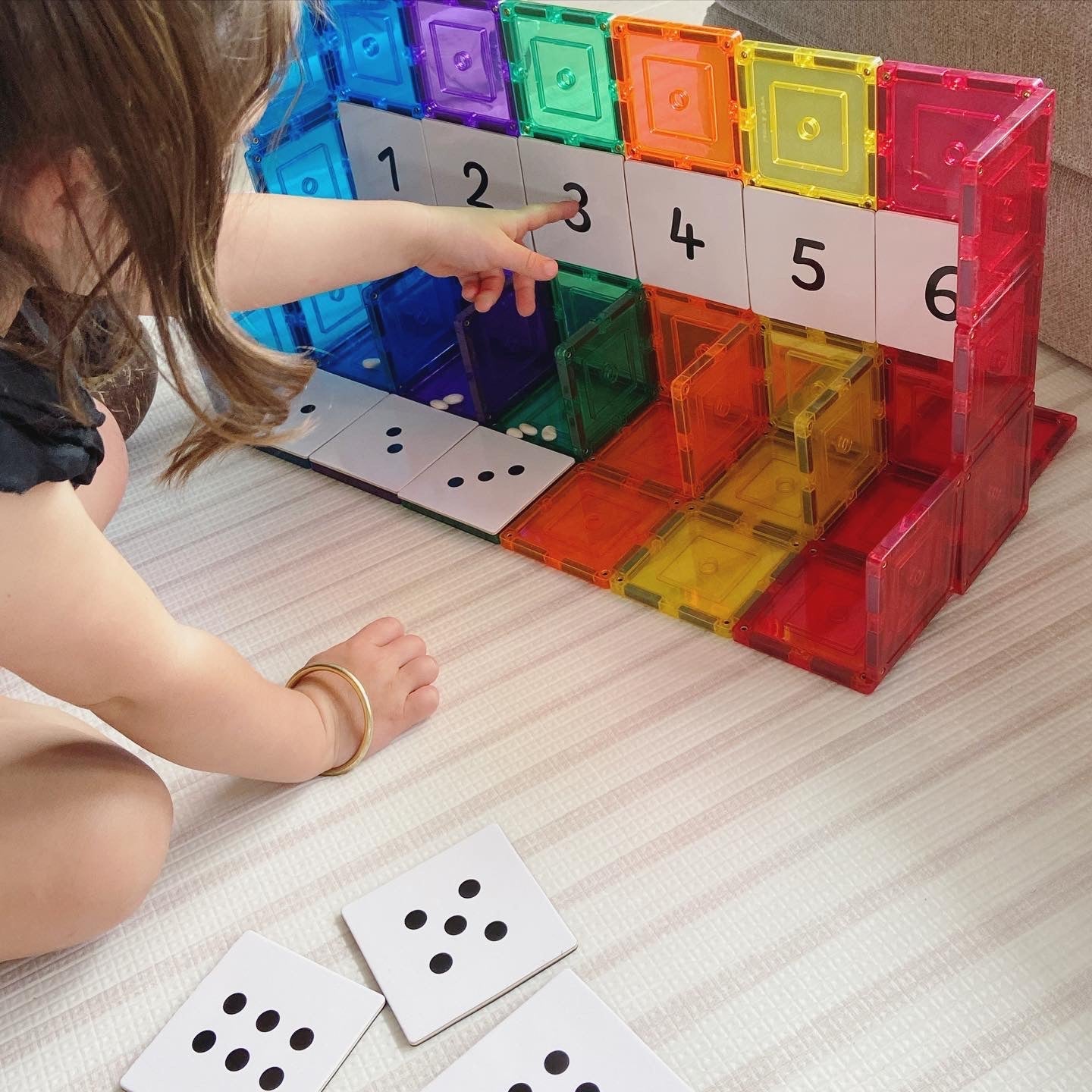 Child playing with Numbers Pack toppers on magnetic tiles