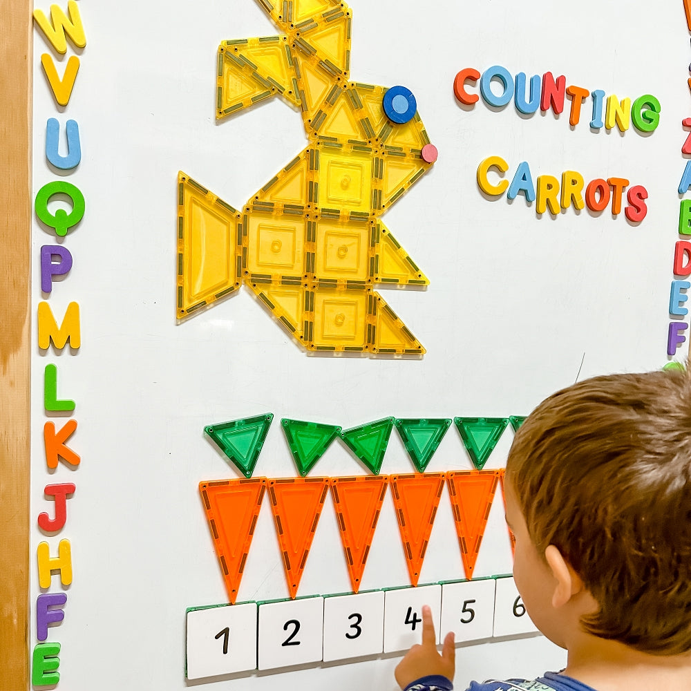 Child counting carrots with Numbers Pack toppers on a whiteboard