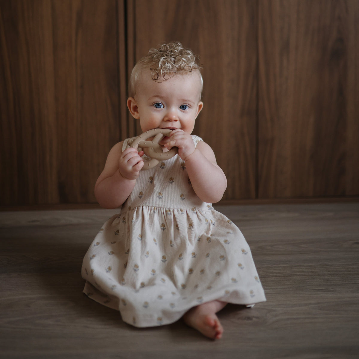 Baby holding the Mushie Pretzel Teether