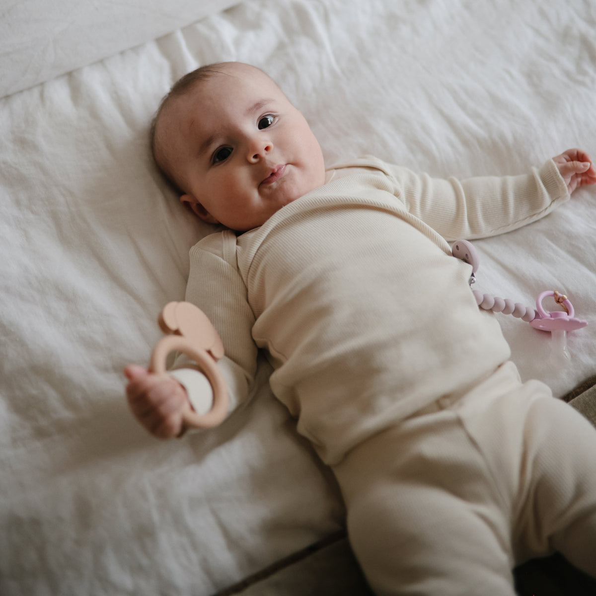 Baby holding the Mushie Dog Teether