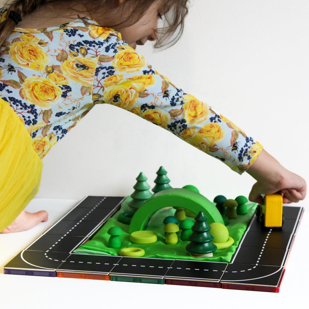 Girl playing with Road Pack tile toppers and a toy car