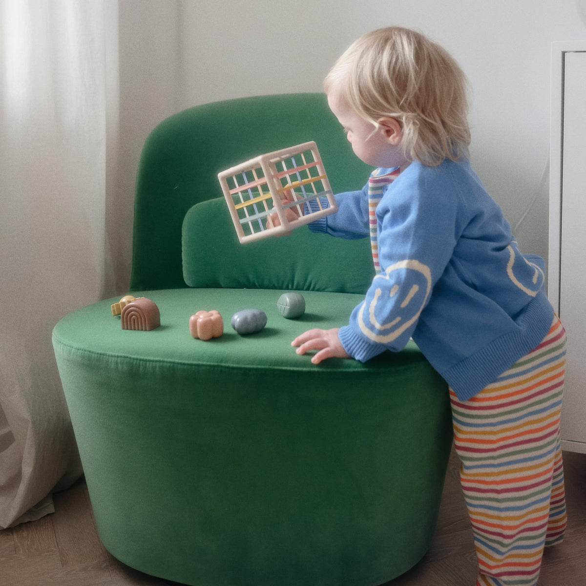 Toddler playing with the Mushie Elastic Shape Sorter