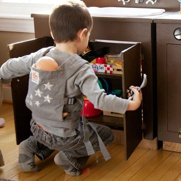 Child carrying a doll in the Ergobaby Doll Carrier