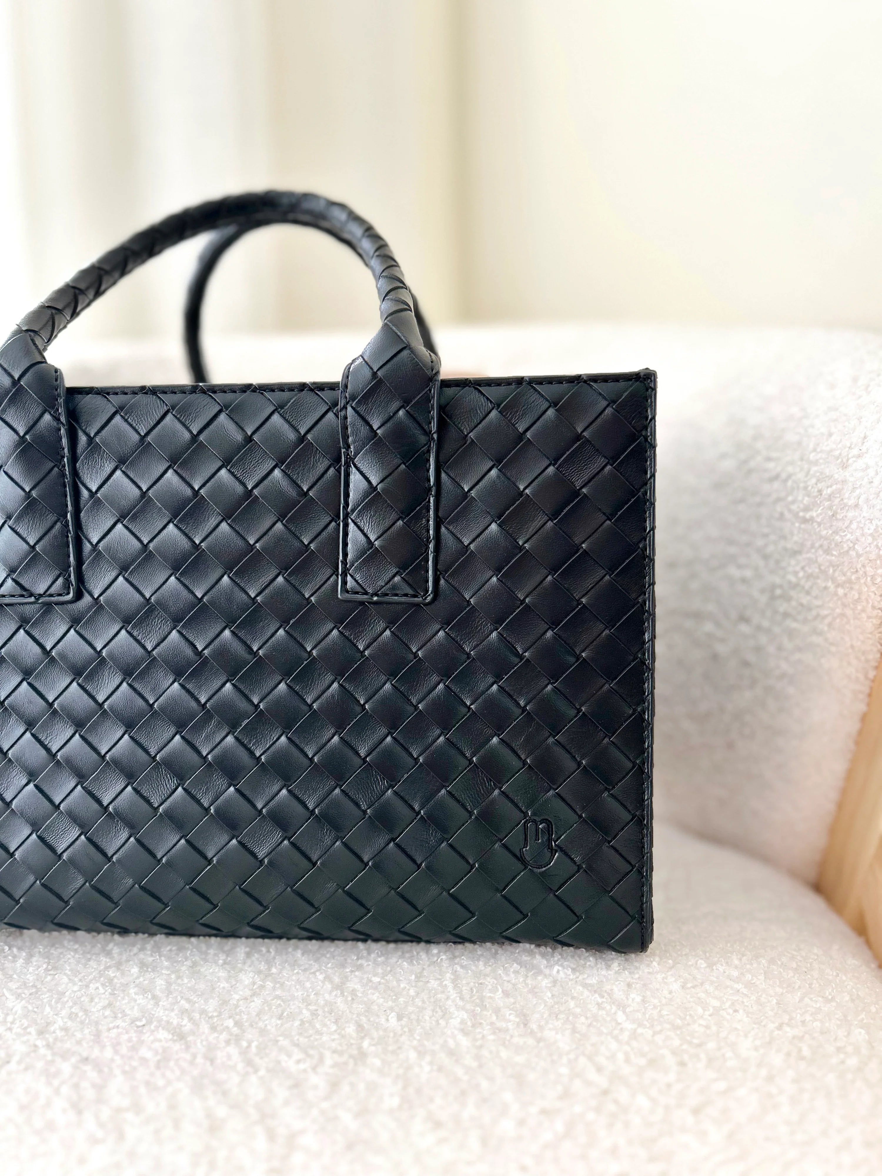 Black woven handbag on a light-colored surface