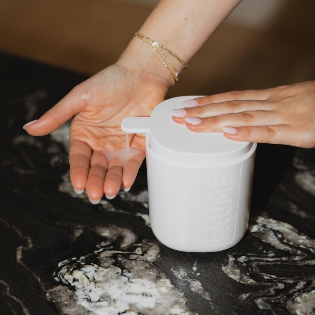 Person using a white container to apply cream or lotion on their hands.