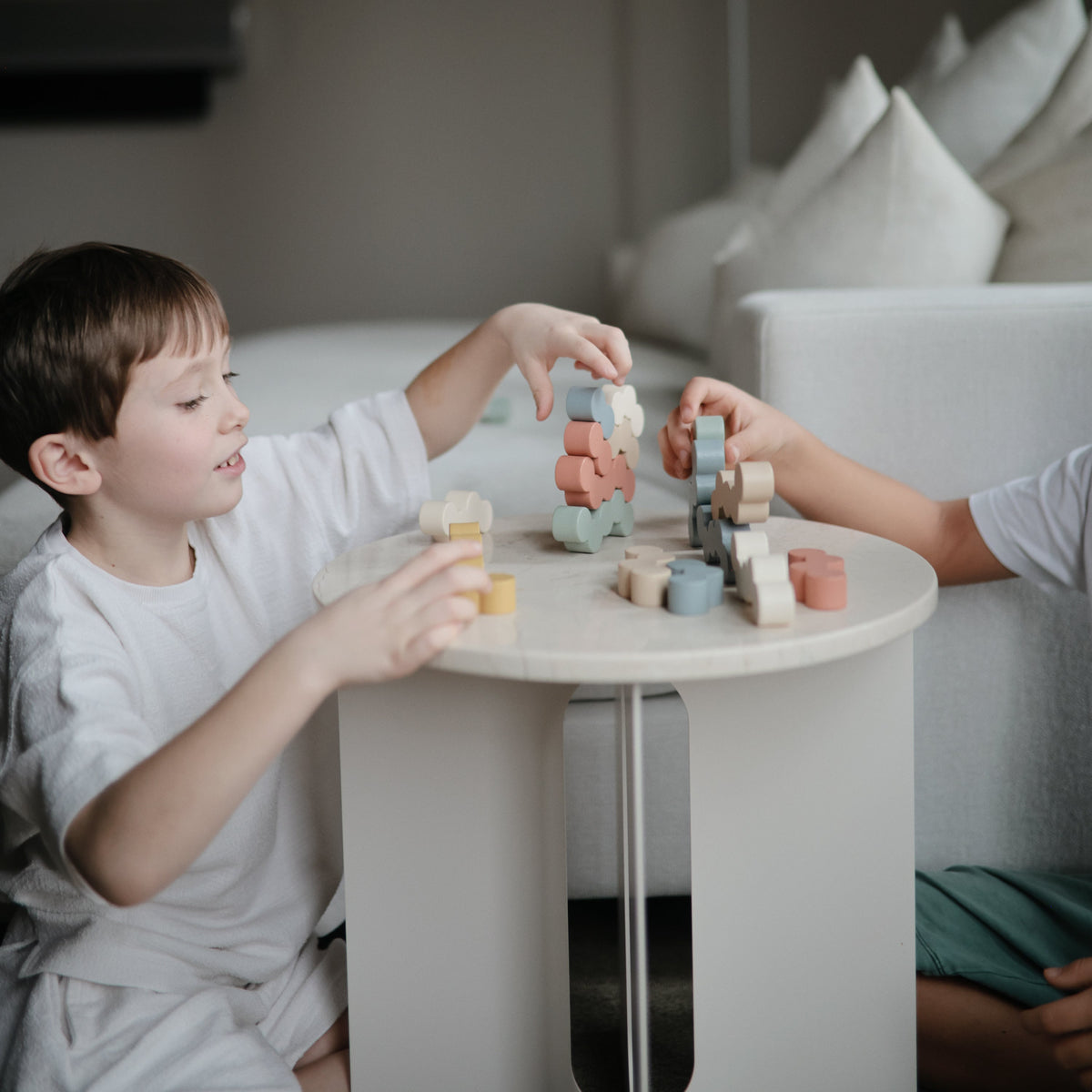 Two children stacking Mushie Wooden Balance Blocks