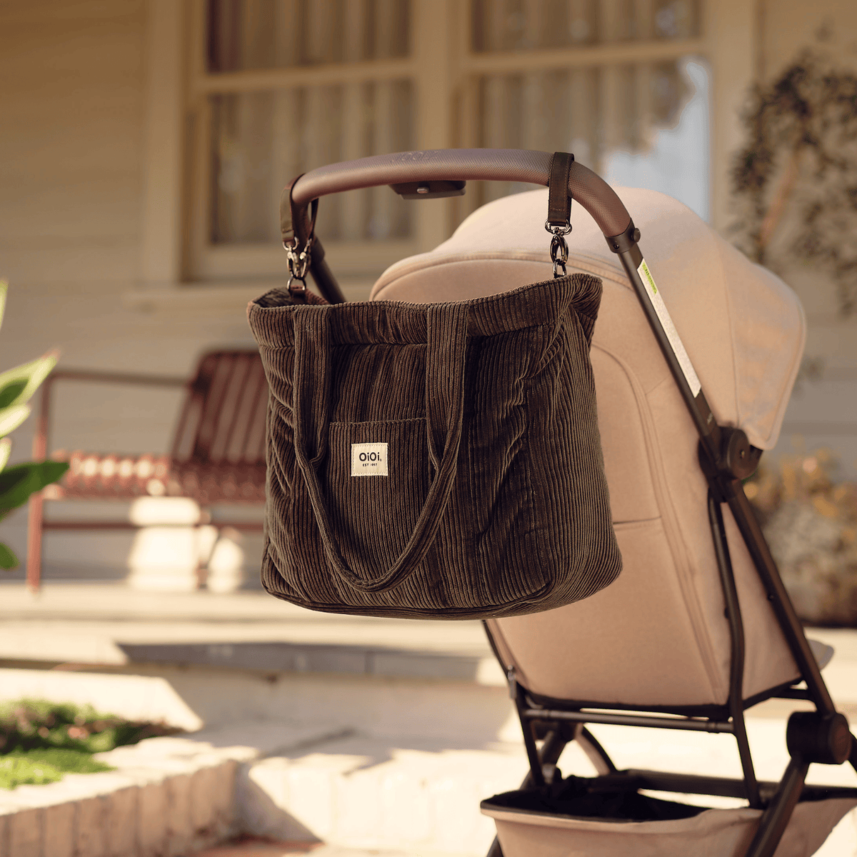 OiOi Everyday Tote nappy bag clipped to a pram with the included stroller straps