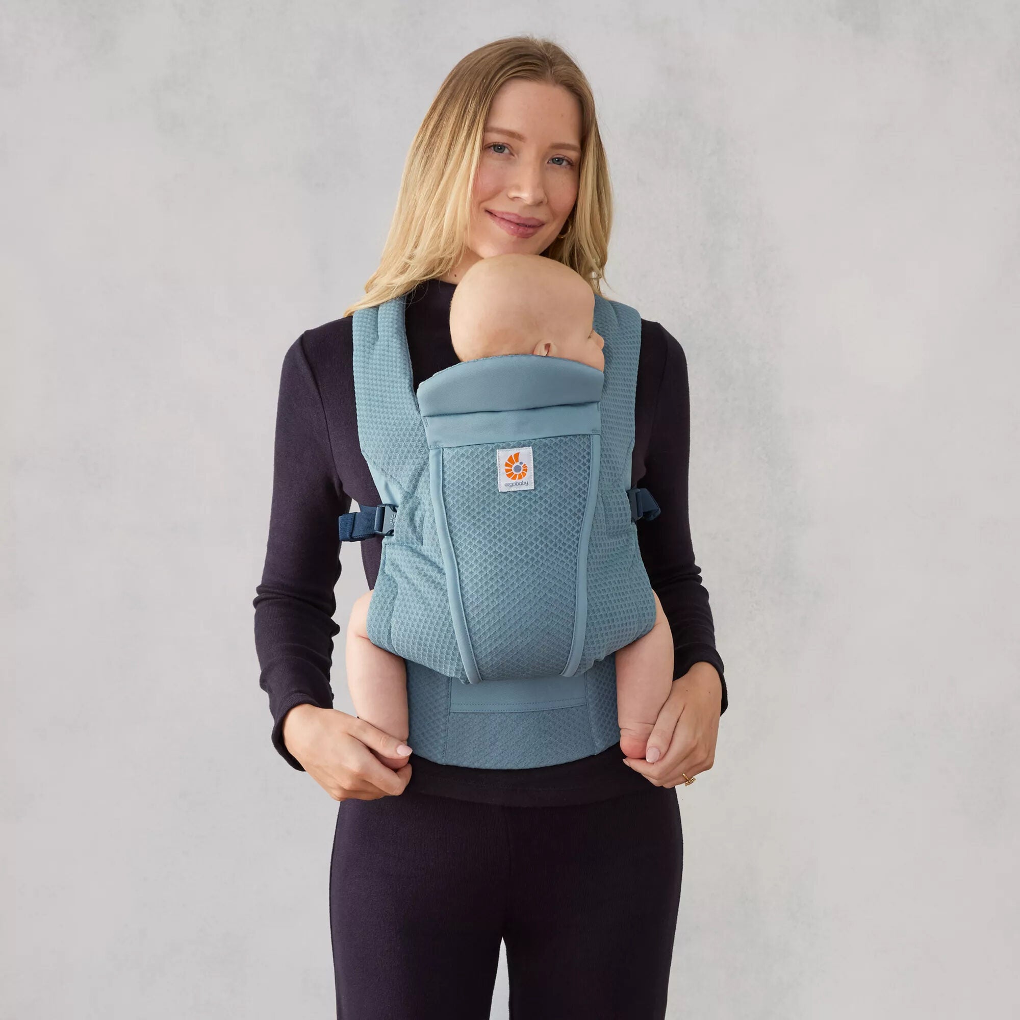 Parent wearing Ergobaby Omni Lite in Slate Blue, front inward carry