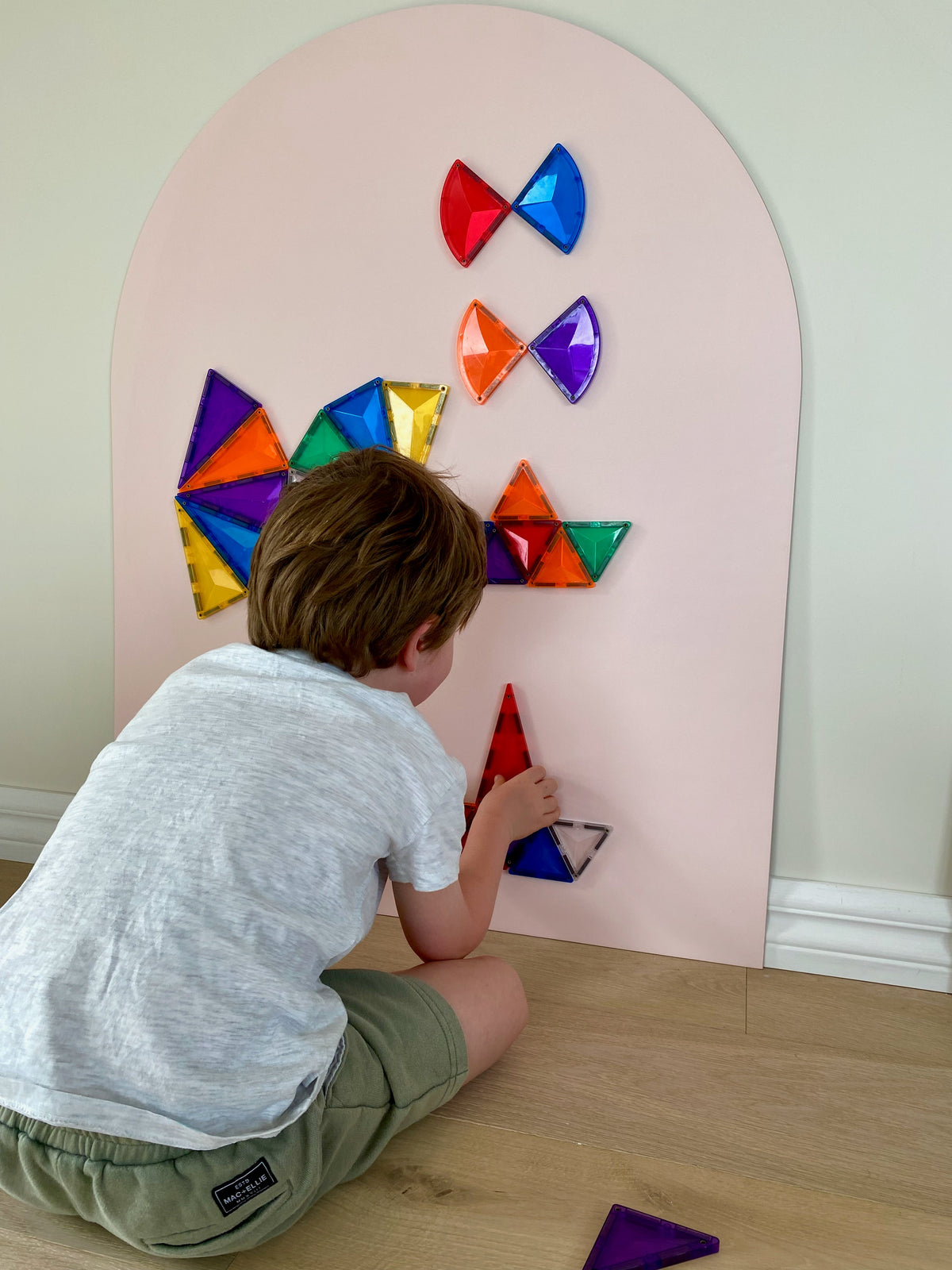 Child playing with magnetic tiles on a Blush Pink MagMe wall decal