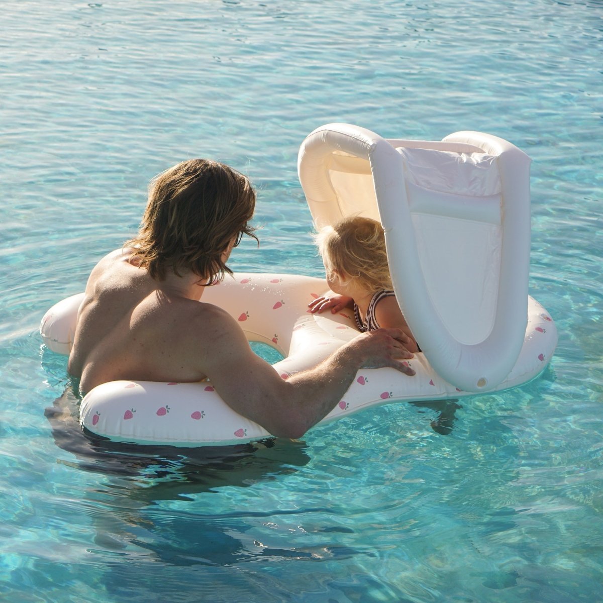 Parent and baby floating together in the Sunnylife Float Together Baby Seat Strawberry Sunshine