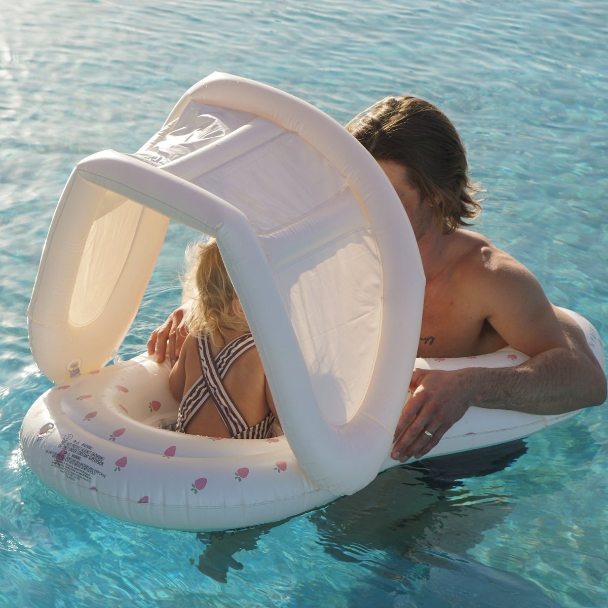 Baby in the Sunnylife Float Together Baby Seat Strawberry Sunshine at the pool