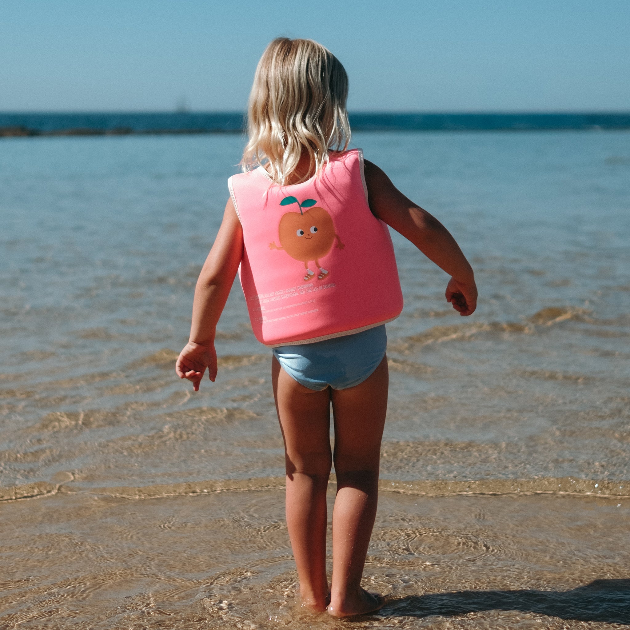 Child wearing the Sunnylife Kids Swim Vest Poppy the Peach Neon Pink