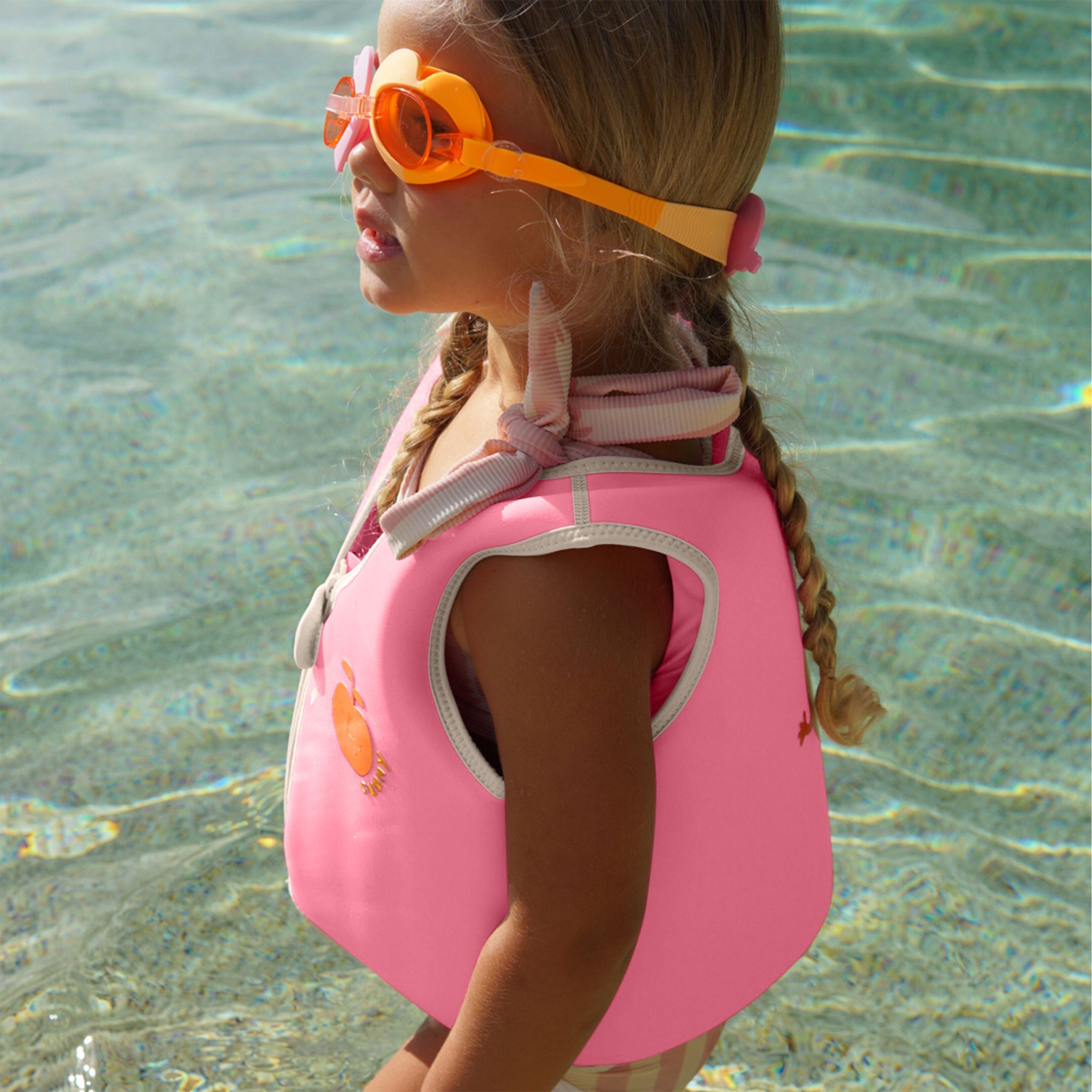 Child swimming in the Sunnylife Kids Swim Vest Poppy the Peach Neon Pink