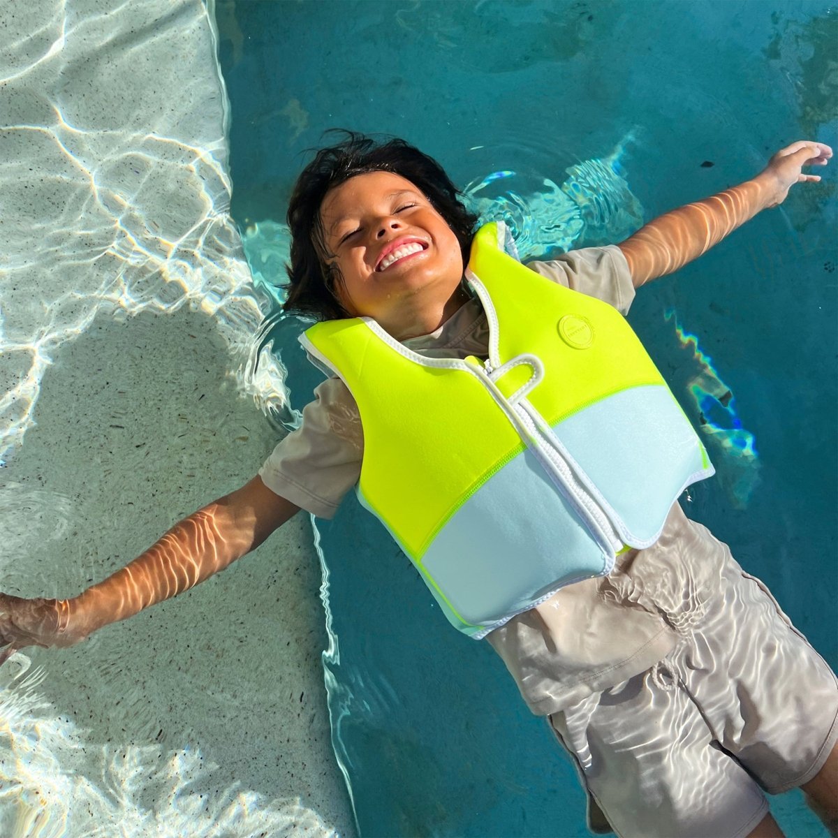 Child swimming in the Sunnylife Kids Swim Vest Salty the Shark Aqua Neon