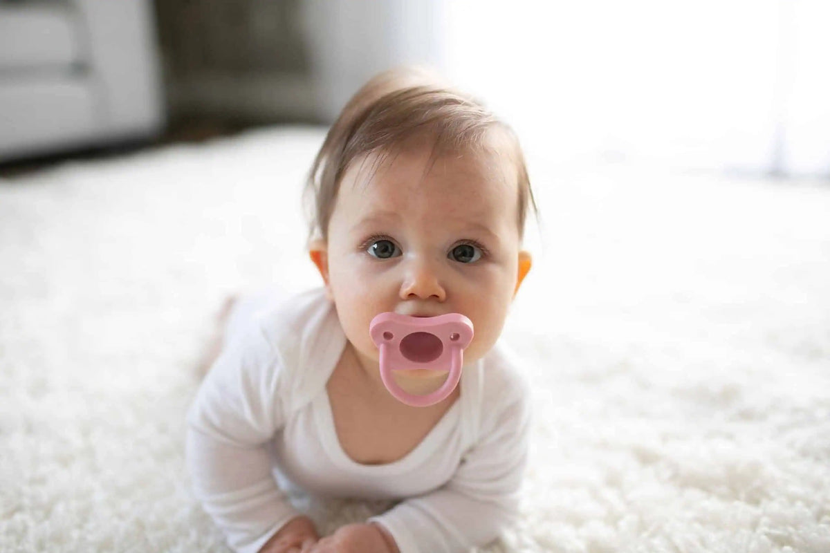 Baby using a pink Dr Brown's HappyPaci silicone soother