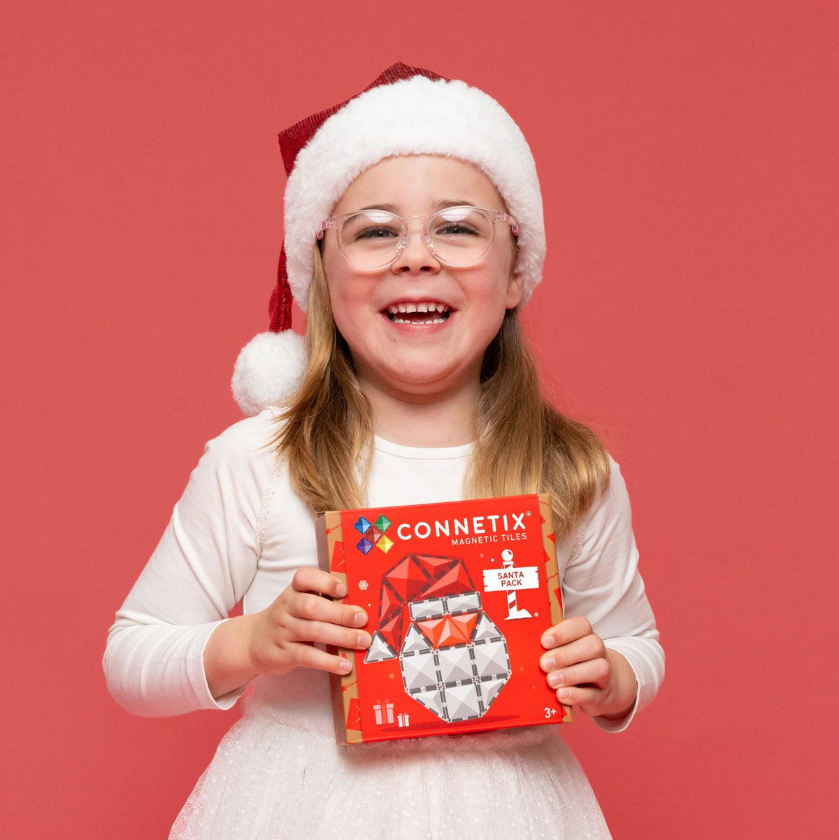 Girl in a Santa hat holding the Connetix Christmas Santa Pack