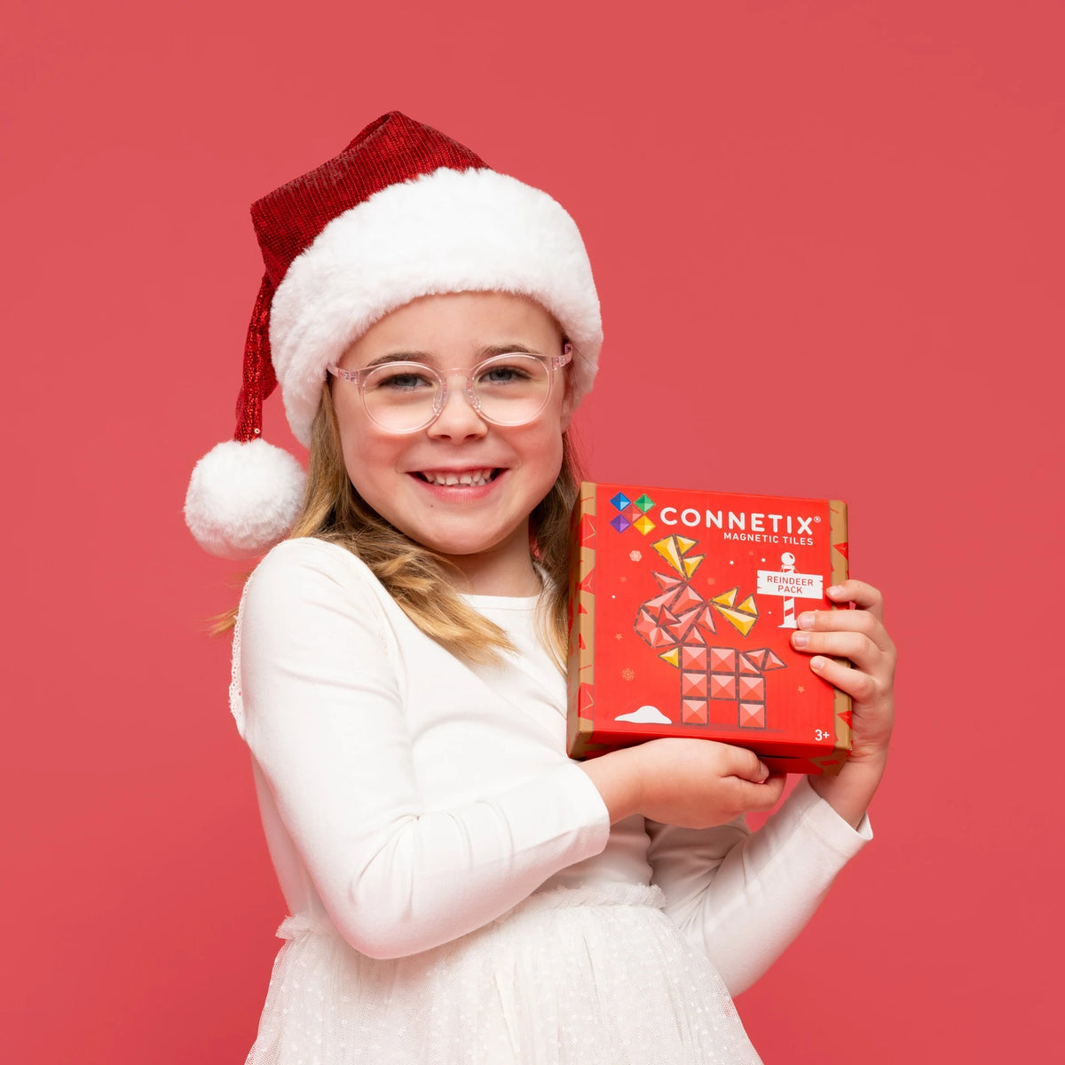 Girl in a Santa hat holding the Connetix Christmas Reindeer Pack