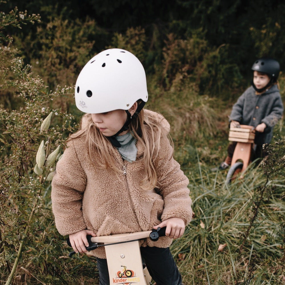 Toddler wearing a Kinderfeets helmet on a balance bike