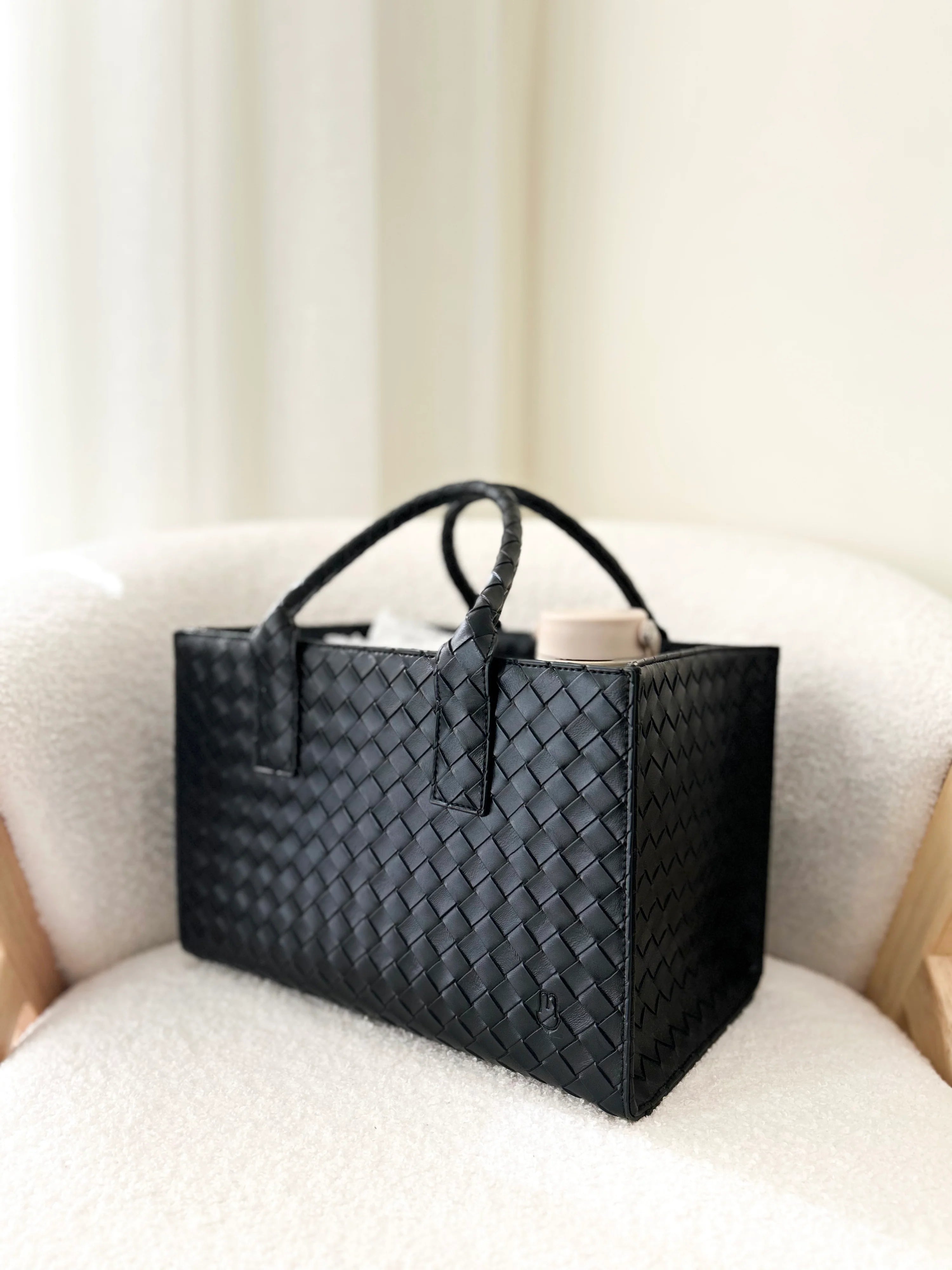 Black woven handbag on a light-colored sofa