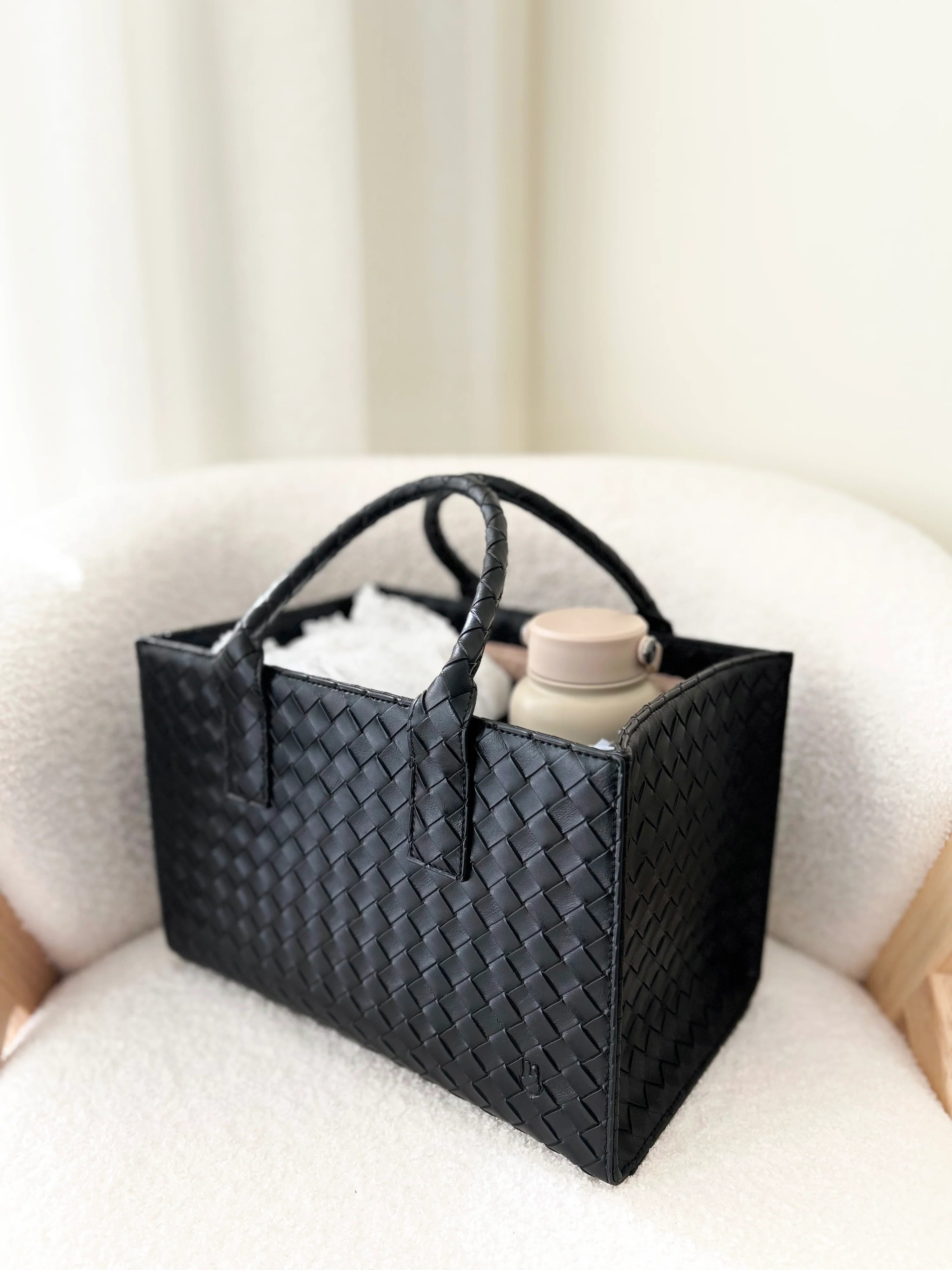 Black woven basket on a white surface with a neutral background