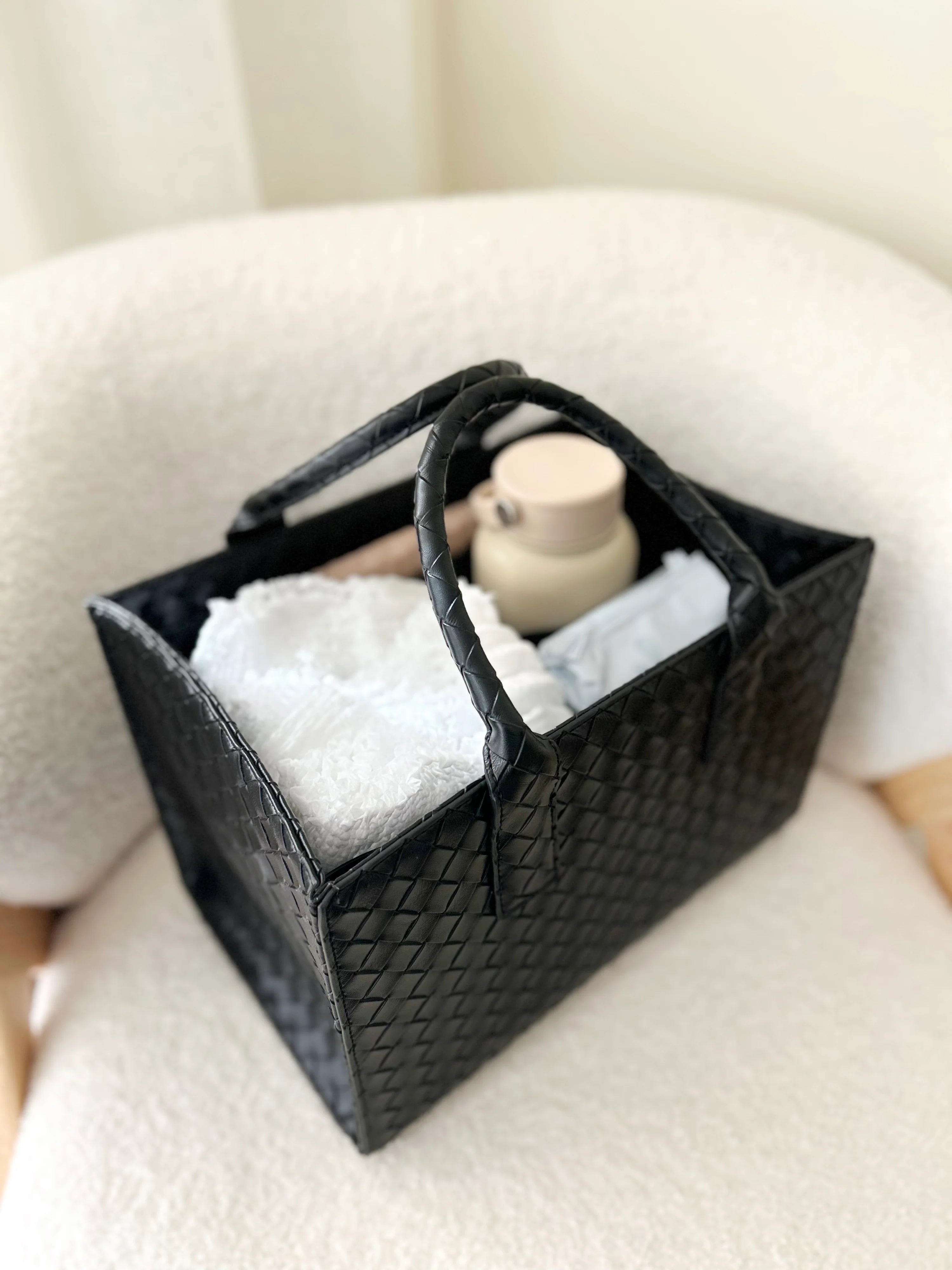 Black woven basket with items on a white surface