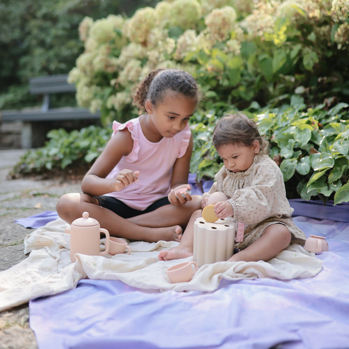 Children playing with the Mushie Coin & Tube Sorting Set outdoors